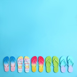 Photo of Different flip flops and space for text on blue background, flat lay. Summer beach accessories