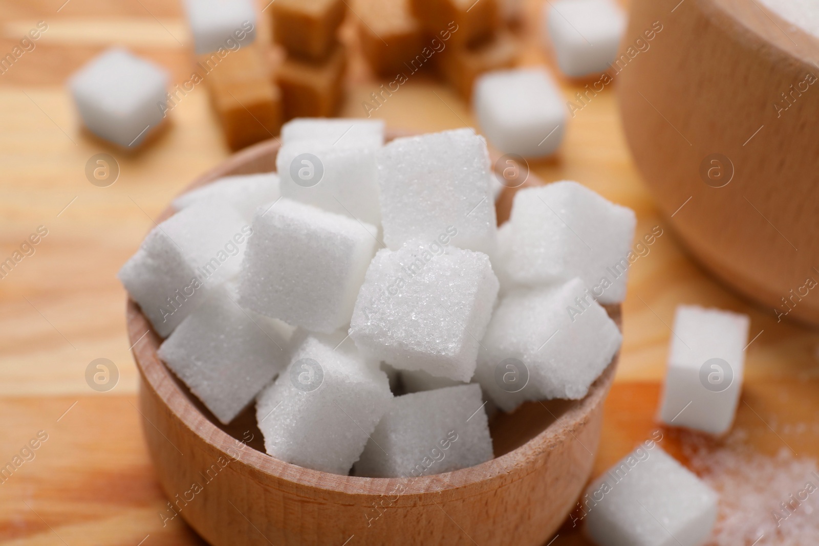 Photo of White sugar cubes in bowl on table, closeup