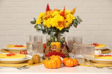 Photo of Autumn table setting with floral decor and pumpkins indoors