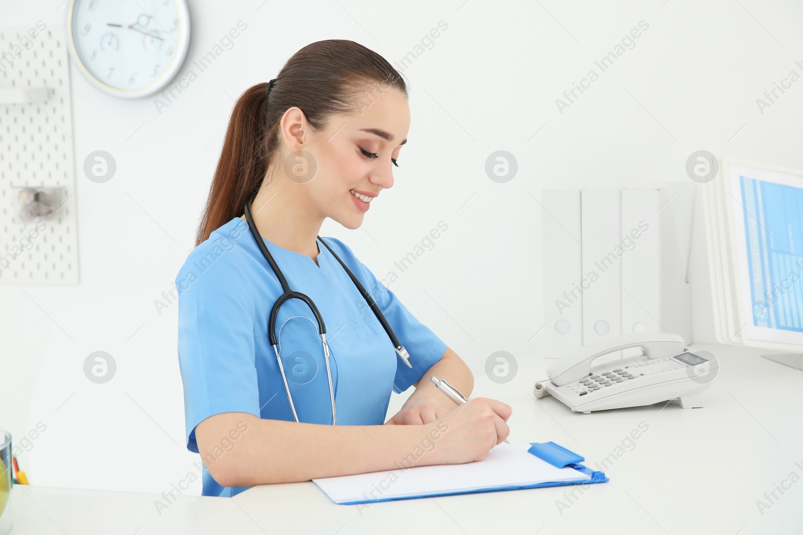 Photo of Young female doctor working at reception desk in hospital