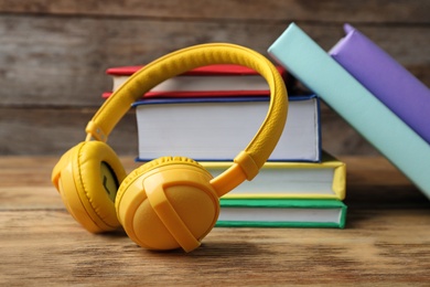 Photo of Modern headphones with hardcover books on wooden table, closeup