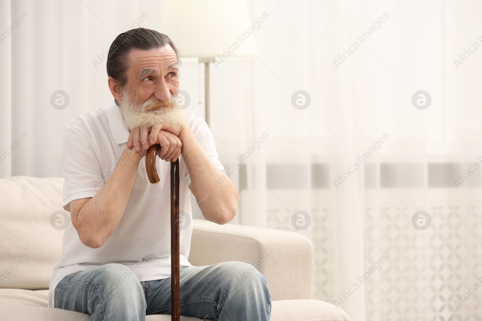 Photo of Senior man with walking cane on sofa at home