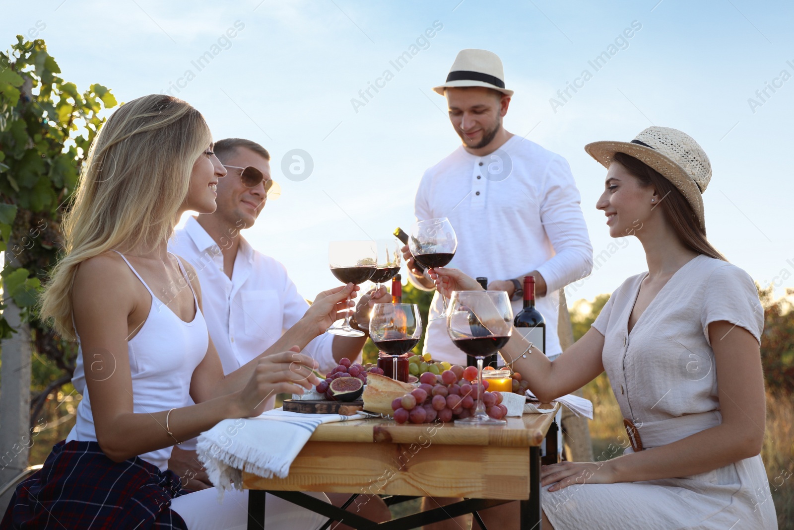 Photo of Friends holding glasses of wine and having fun in vineyard