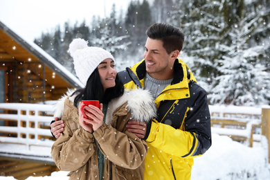 Photo of Happy couple with hot drink at resort. Winter vacation