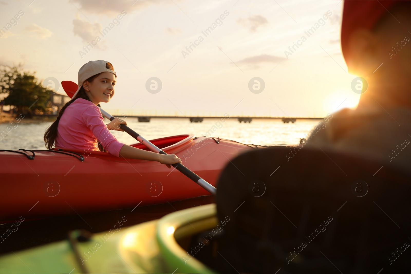 Photo of Children kayaking on river at sunset. Summer camp activity