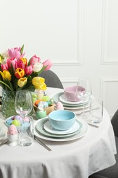 Photo of Easter celebration. Festive table setting with beautiful flowers and painted eggs