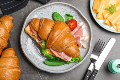 Flat lay composition with tasty croissant sandwich on grey table