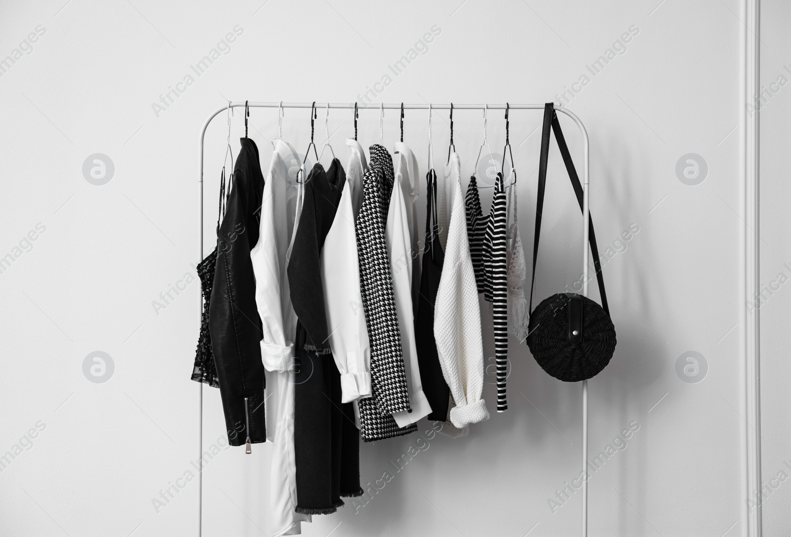 Photo of Rack with stylish clothes near white wall