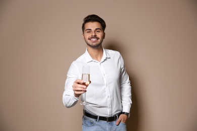 Photo of Handsome man with glass of champagne on color background