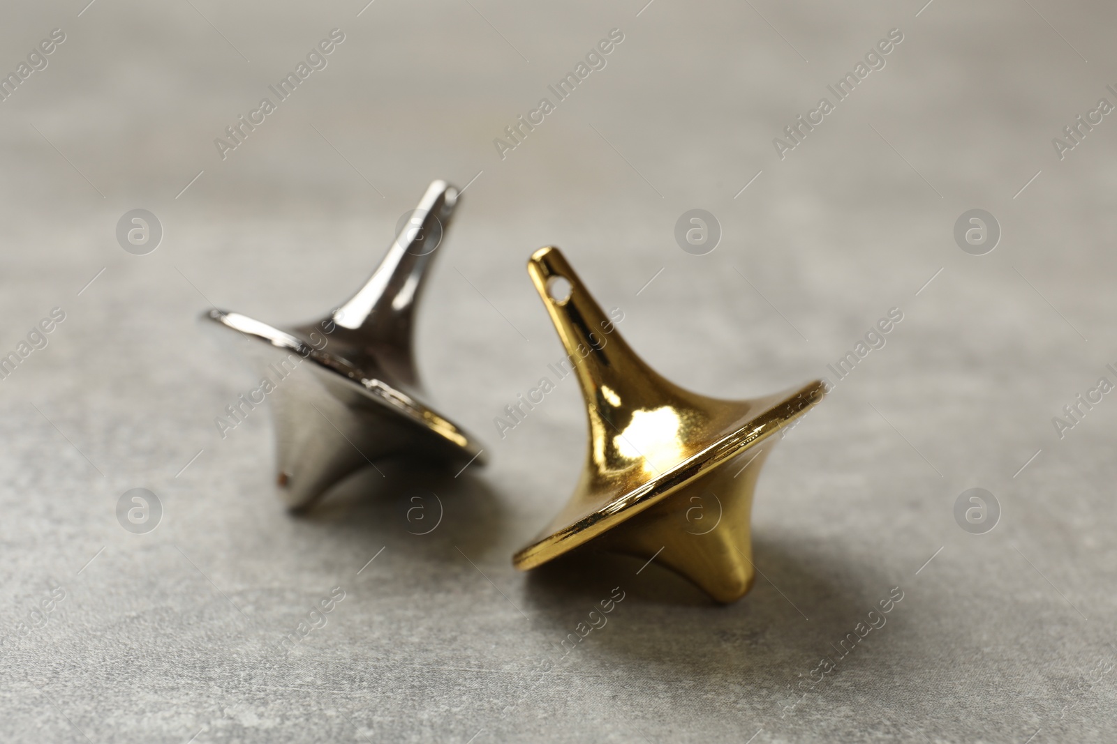Photo of Metal spinning tops on grey textured background, closeup
