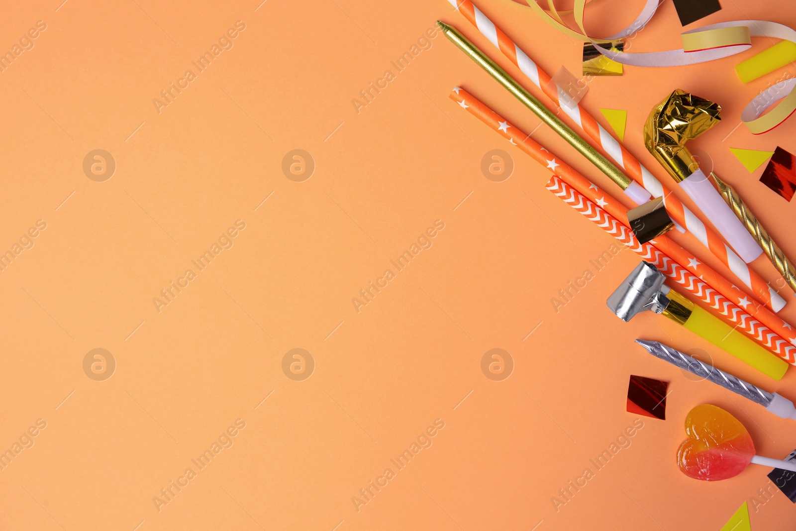 Photo of Party blowers, lollipop and festive decor on coral background, flat lay. Space for text