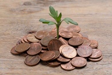 Photo of Coins with green sprout on wooden table, closeup. Investment concept