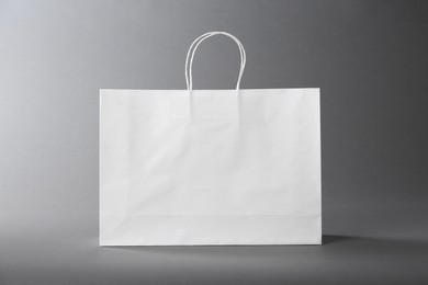 Photo of One white paper bag on grey background. Mockup for design