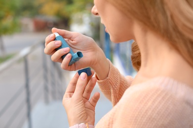 Photo of Woman using asthma inhaler outdoors, closeup. Health care