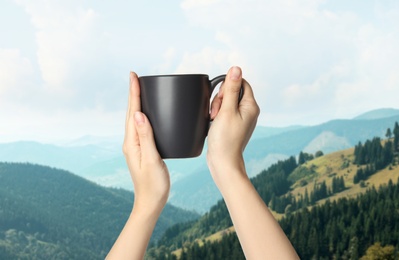 Closeness to nature. Woman holding cup in mountains, closeup