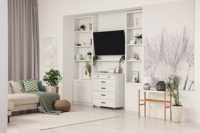 Photo of Stylish living room interior with comfortable sofa, TV set and houseplants