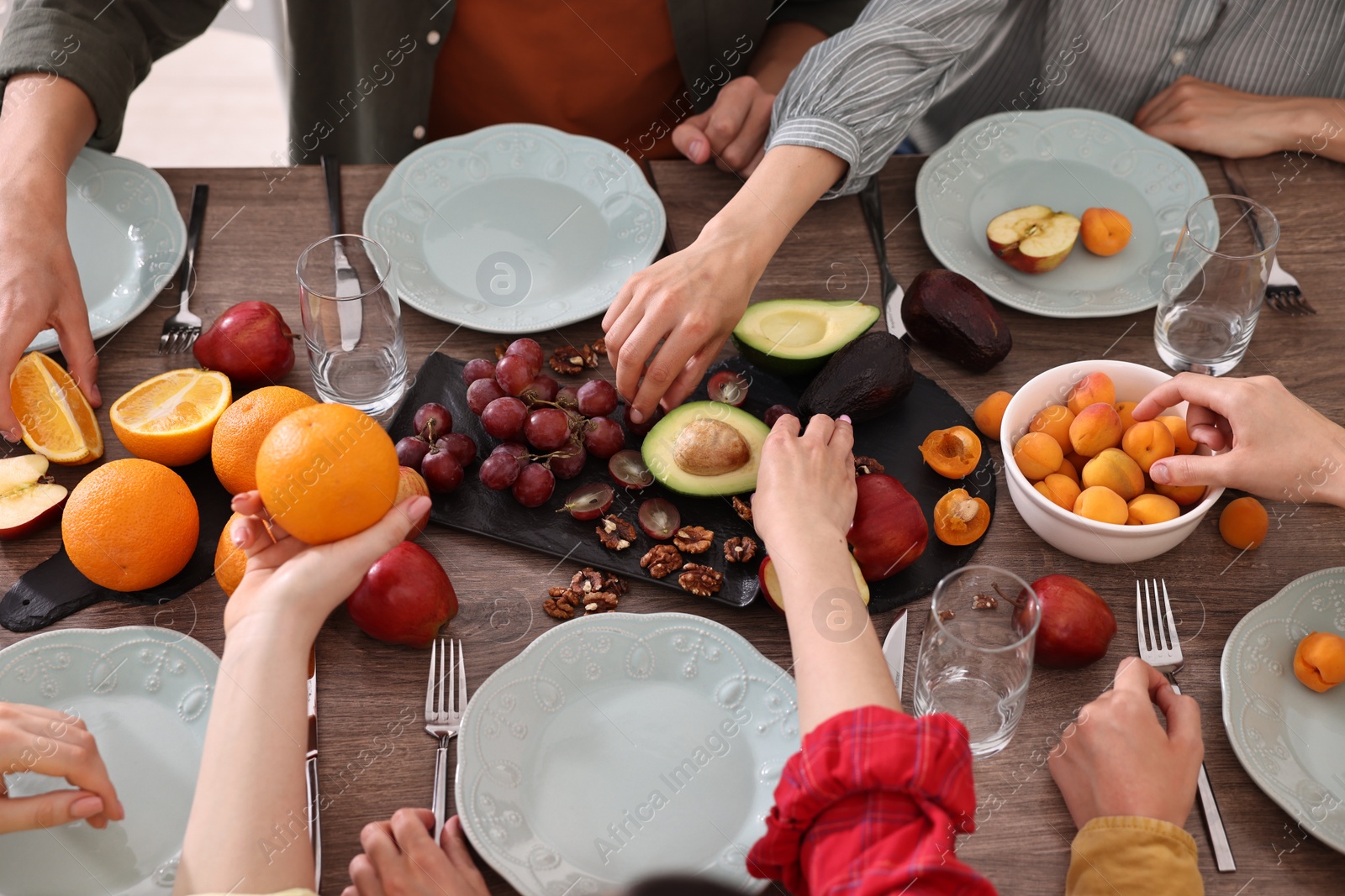 Photo of Friends eating vegetarian food at wooden table indoors, closeup