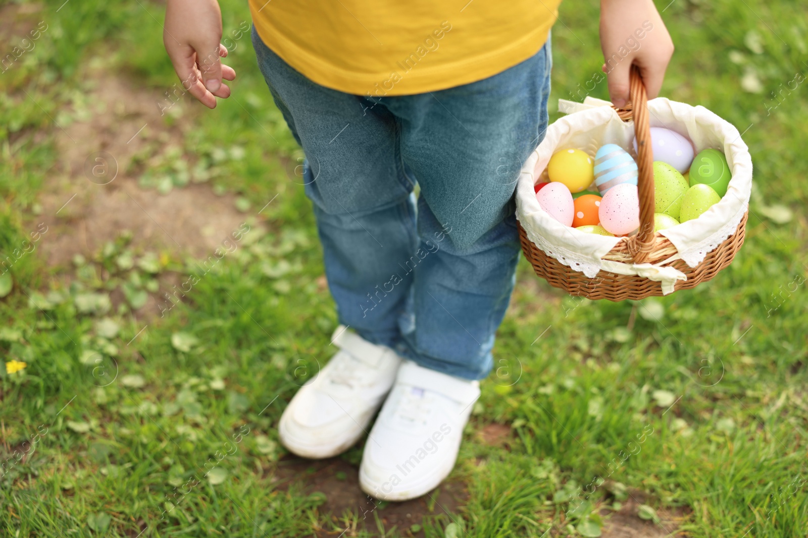 Photo of Easter celebration. Little boy holding basket with painted eggs outdoors, closeup