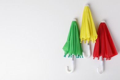 Photo of Small color umbrellas on white background, top view. Space for text
