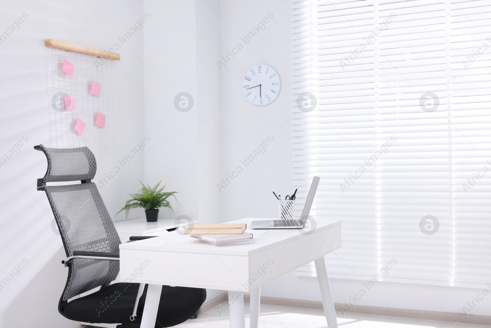 Photo of Desk and comfortable chair in modern office, space for text. Interior design