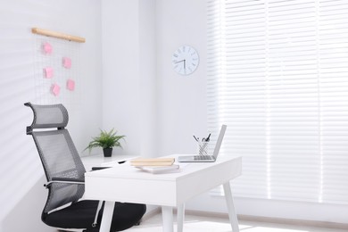 Photo of Desk and comfortable chair in modern office, space for text. Interior design