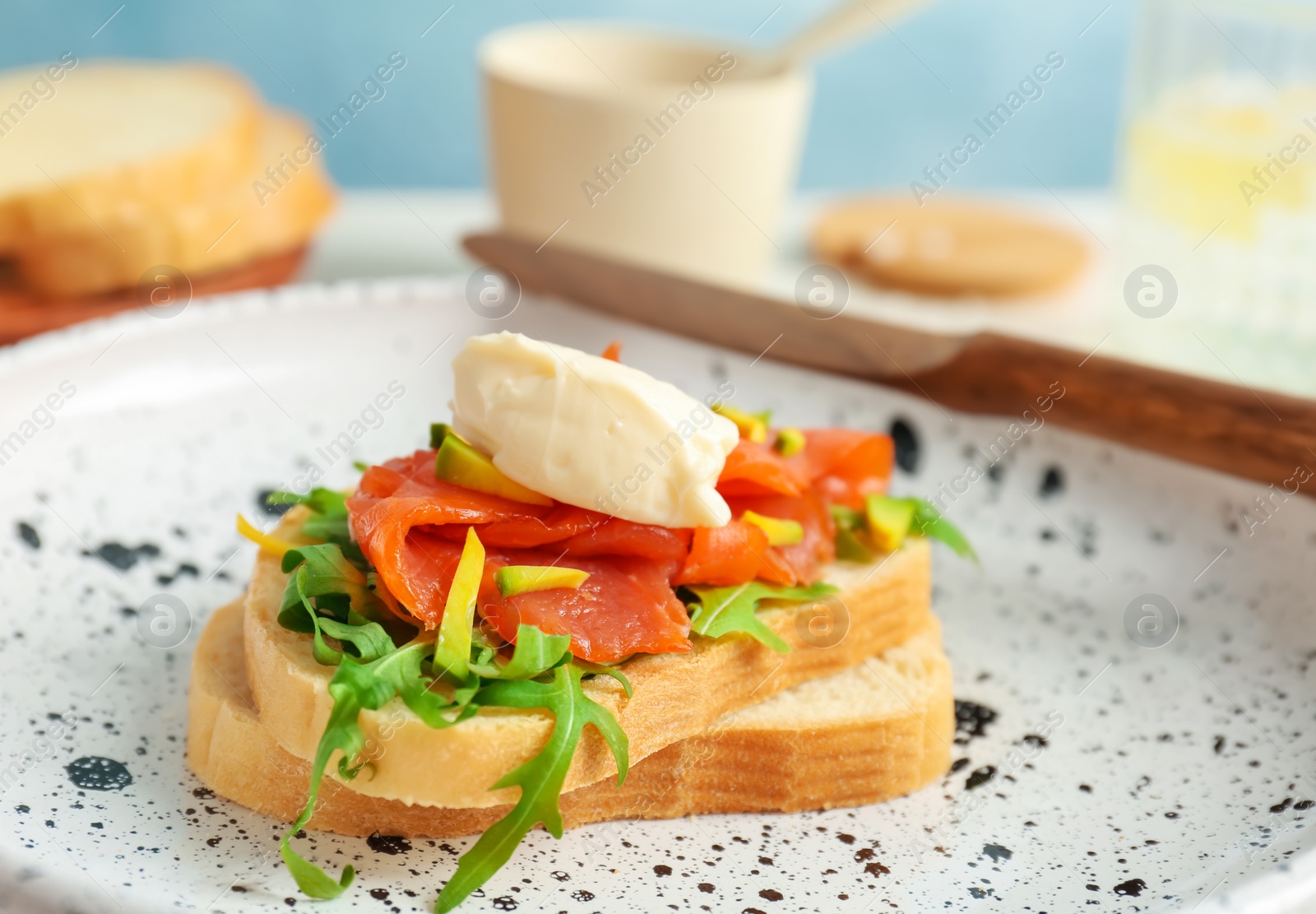 Photo of Sandwich with fresh sliced salmon fillet and avocado on plate, closeup