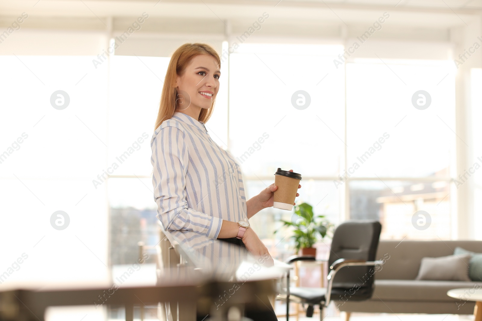 Photo of Young businesswoman with cup of coffee relaxing in office during break