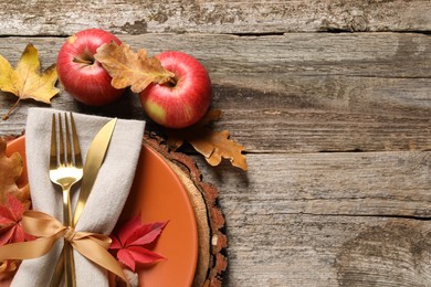 Photo of Festive table setting with autumn decor and apples on wooden background, flat lay. Space for text