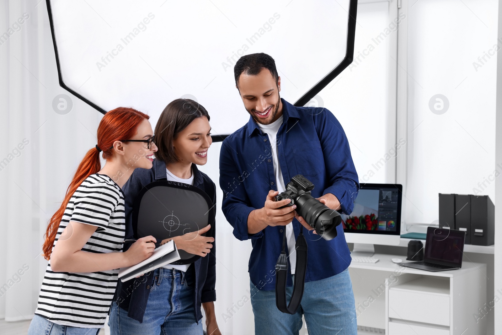 Photo of Young professional photographers working in modern photo studio, space for text