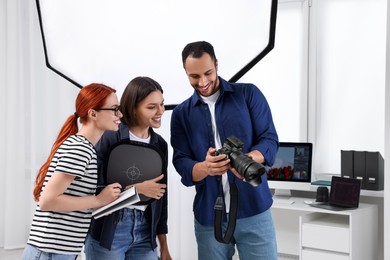 Photo of Young professional photographers working in modern photo studio, space for text