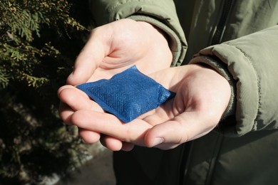 Photo of Man holding hand warmer outdoors, closeup view