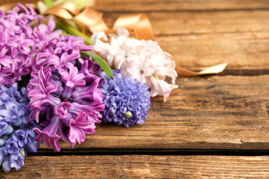 Photo of Beautiful spring hyacinth flowers on wooden table, closeup. Space for text
