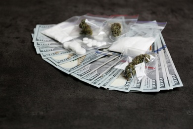 Photo of Plastic bags with cocaine, pills, hemp buds and money on grey background