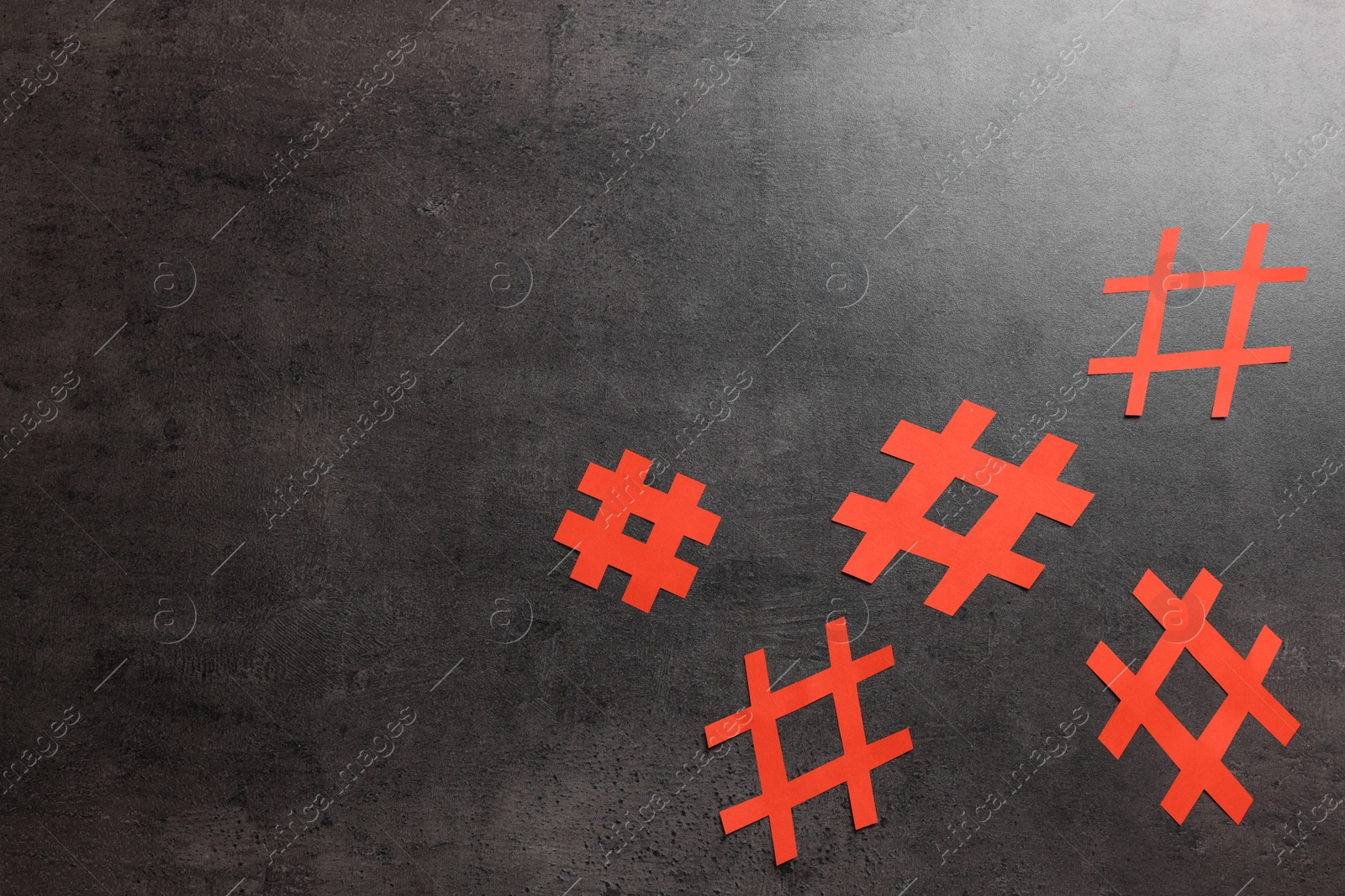 Photo of Red paper cutout symbols of hashtag on dark background, flat lay. Space for text