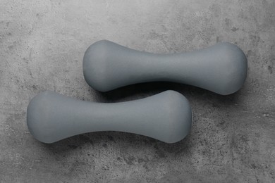 Photo of Grey dumbbells on brown textured table, top view