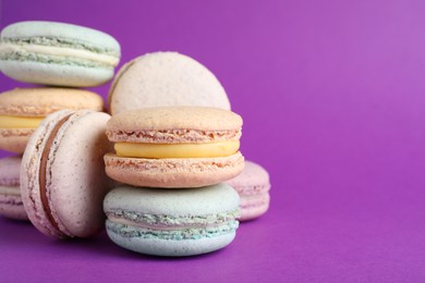 Photo of Delicious colorful macarons on purple background, closeup. Space for text