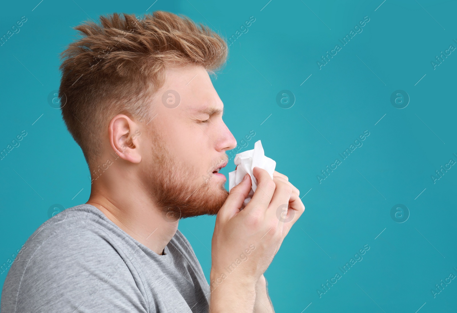 Photo of Young man suffering from allergy on blue background. Space for text