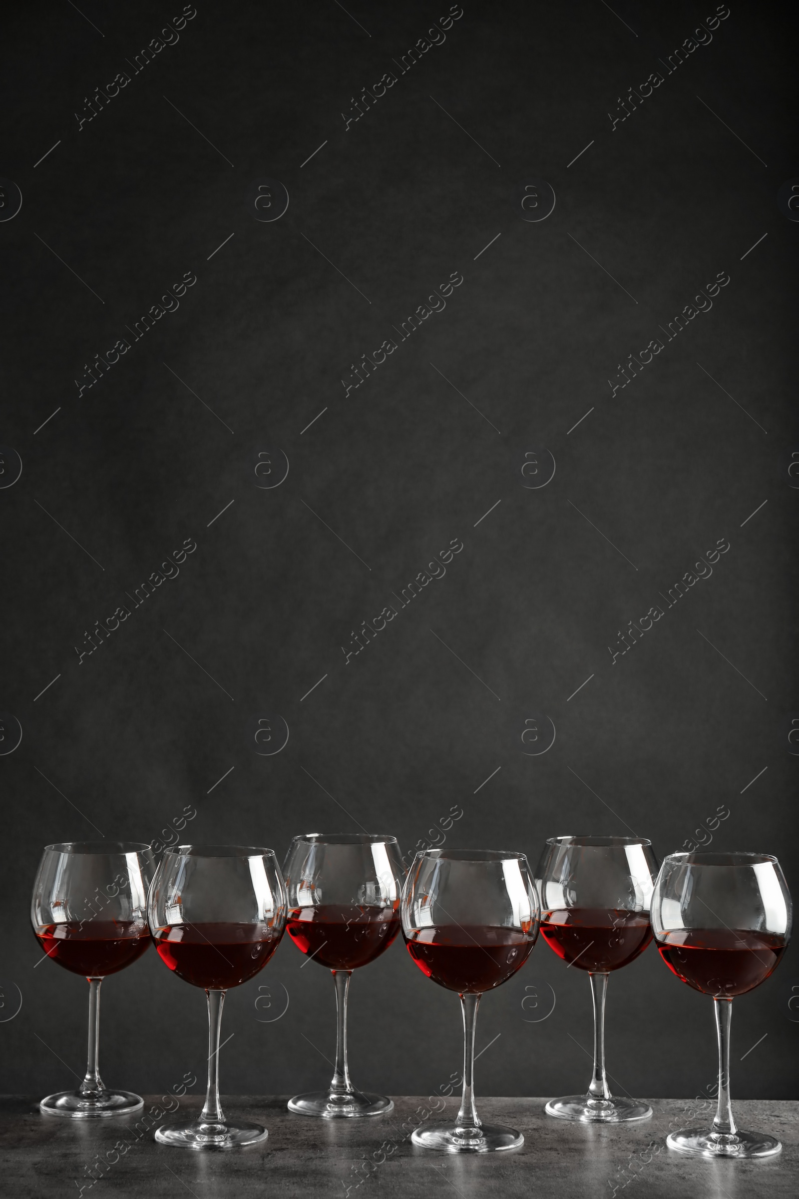 Photo of Glasses with red wine on table against dark background