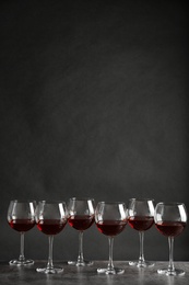 Glasses with red wine on table against dark background