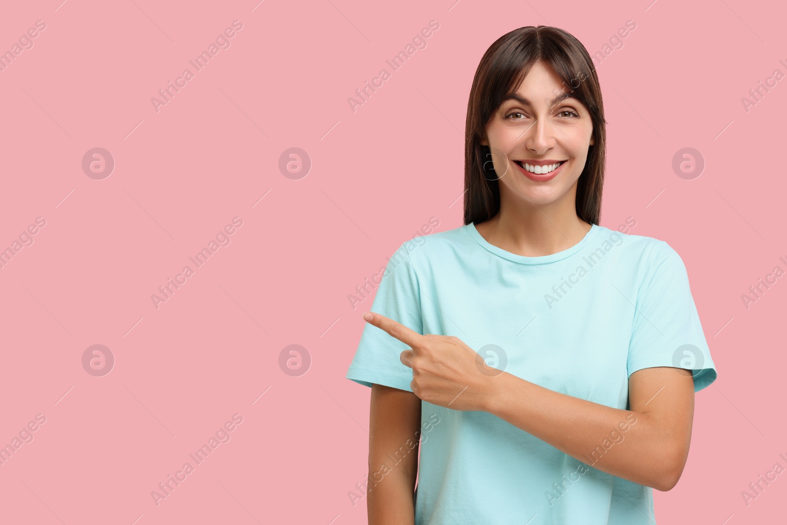 Photo of Special promotion. Happy woman pointing at something on pink background, space for text