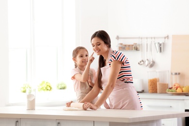 Photo of Mother and her daughter preparing dough at table in kitchen