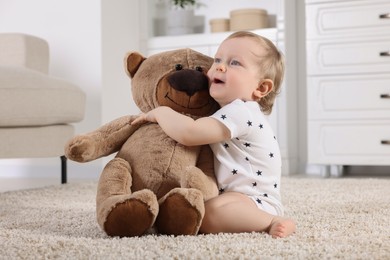 Cute little child with teddy bear on carpet at home