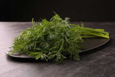 Photo of Sprigs of fresh dill on dark textured table, closeup