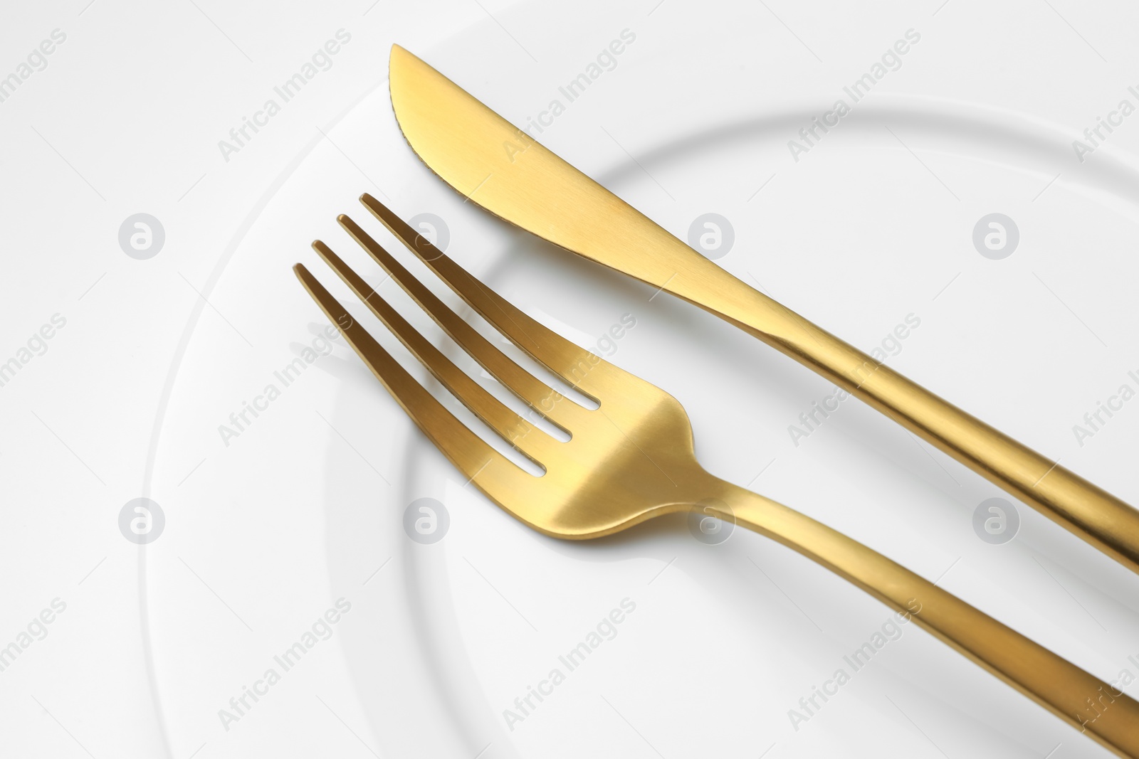 Photo of Clean plate, fork and knife on white background, closeup