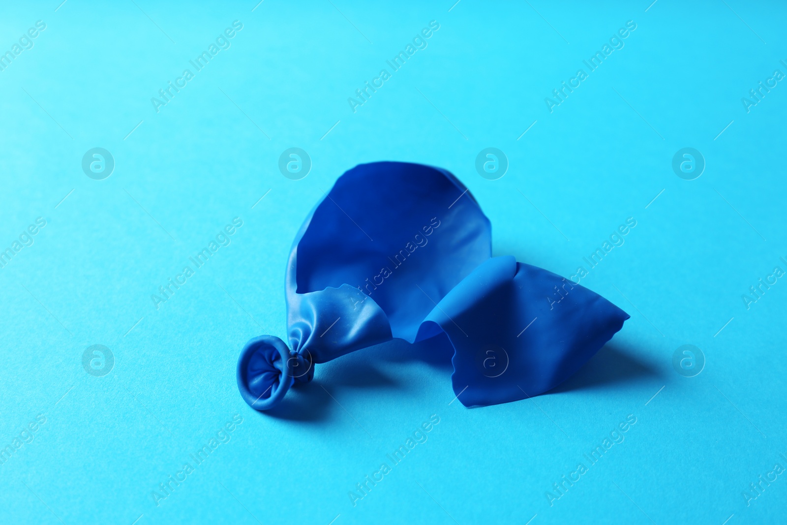 Photo of Popped blue latex balloon on color background