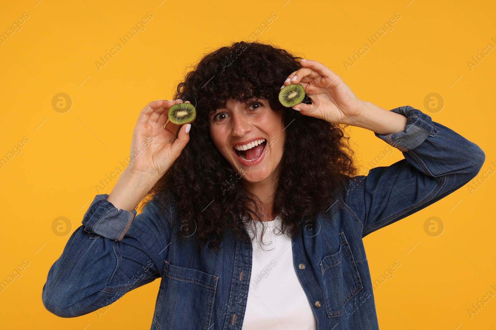 Photo of Woman holding halves of kiwi on yellow background