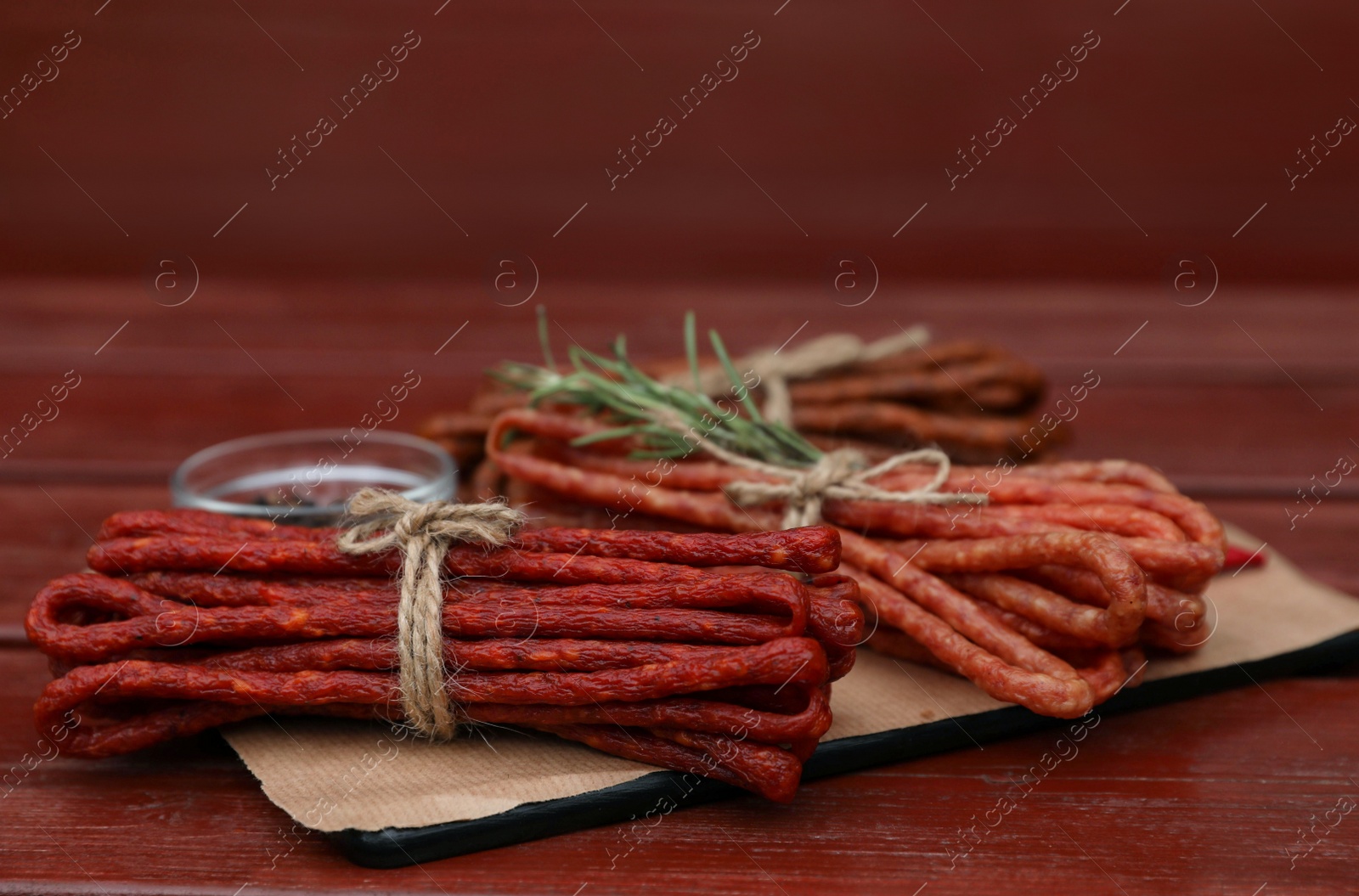 Photo of Bundles of delicious kabanosy on wooden table