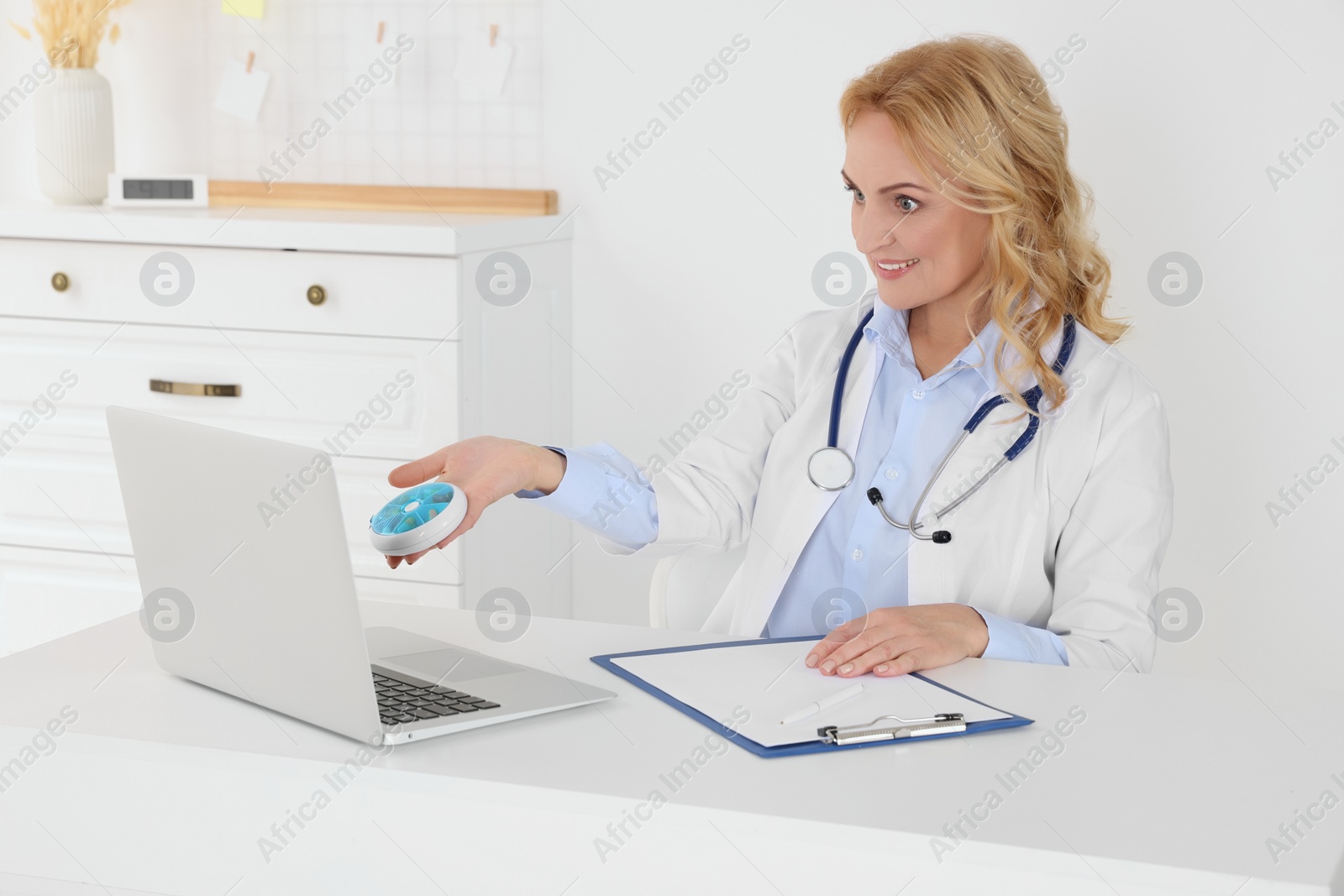 Photo of Doctor with laptop and pills consulting patient in clinic. Online medicine concept