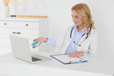 Photo of Doctor with laptop and pills consulting patient in clinic. Online medicine concept