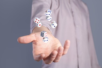 Image of Man throwing white dice on grey background, closeup